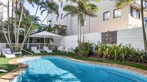 Una piscina con lettini, palme e un edificio con una statua di Buddha.
