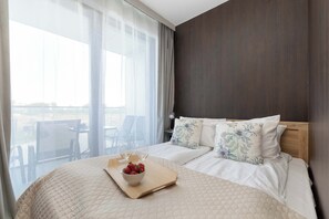 Hotellihuone, jossa on sänky, puinen tarjotinalusta mansikoineen, kulho ja näkymä ulos.