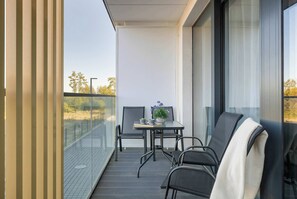 Ein Balkon mit Tisch, Stühlen und einem Blumentopf.