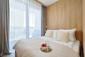 Ein Hotelzimmer mit Bett, Fenster mit Vorhängen und Blick ins Freie.