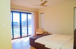 Ein Schlafzimmer mit einem großen Bett, einem Sessel, einem kleinen Tisch und einem Deckenventilator.