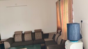 A living room with a sofa, a green coffee table, and a white heater. - Woodcock Cottage (Ooty)