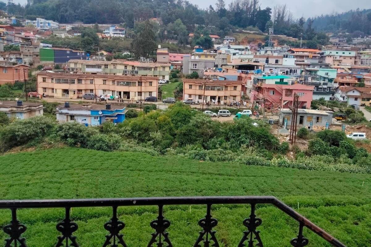 Un barrio residencial con casas, un campo verde y una barandilla metálica.