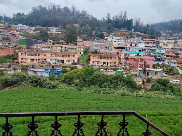 A residential area with houses, a green field, and a metal railing.