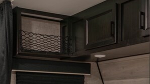 A bed with white bedding and a fluffy pillow, a dark headboard, and a window with a mesh screen. - Cozy Camper w/Pool · Cabo Rojo Lighthouse ·Combate (Boquerón)