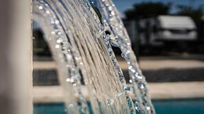 A close-up of a water feature with a reflective surface and a blurred background.
