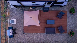 A rooftop patio with a table, chairs, a large umbrella, and potted plants. - Cozy Camper w/Pool · Cabo Rojo Lighthouse ·Combate (Boquerón)
