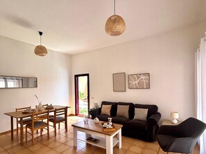 A living room with a dining area, a sofa, and two hanging lights. - Tajora House by Best Holidays Fuerteventura (Corralejo)
