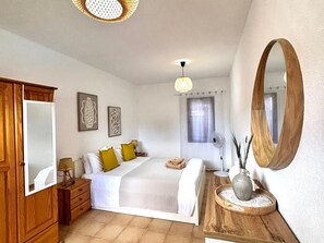 A bedroom with a bed, bedside table, mirror, and artwork on the wall. - Tajora House by Best Holidays Fuerteventura (Corralejo)