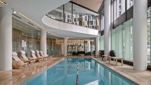 An indoor swimming pool with lounge chairs and a seating area. - Docklands Marina Waterfront Luxury with 180° Views Pool, Gym & Carpark (Docklands)