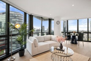 Ein modernes Wohnzimmer mit einer Couch, einem Esstisch und einem großen Fenster mit Blick auf die Stadt.