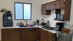Une cuisine moderne avec des meubles de couleur marron, une cuisinière à gaz, un four à micro-ondes et une fenêtre.