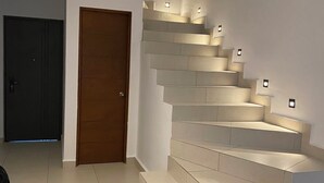 Un intérieur moderne avec un escalier, un coin repas et une porte.