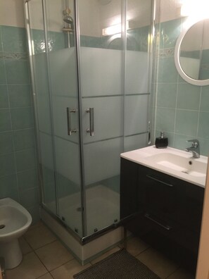 A bathroom with a glass-enclosed shower, a white sink with a black soap dispenser, and a toilet. - Res. Suarella, a beautiful, fully equipped two-bedroom apartment with breathtaking views of the Gulf of Saint-Florent! (Saint-Florent)