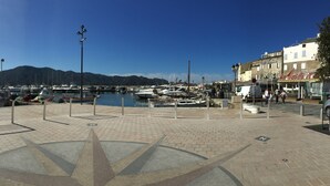 Un puerto deportivo con barcos amarrados, un camino pavimentado y un diseño de rosa de los vientos en el suelo.