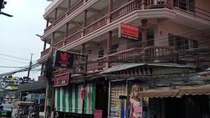 A multi-story building with balconies, a signboard, and a storefront with a green and white striped awning. - Nanas Apartment Pattaya (Muang Pattaya)