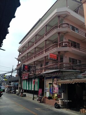 A multi-story building with balconies, a signboard, and a storefront with a green and white striped awning. - Nanas Apartment Pattaya (Muang Pattaya)