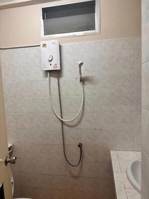 Ein Badezimmer mit Dusche, Toilette und Fenster.
