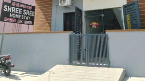 A multi-story building with balconies, air conditioning units, and a signboard advertising a home stay. - Deluxe Room (Tiruvannamalai)