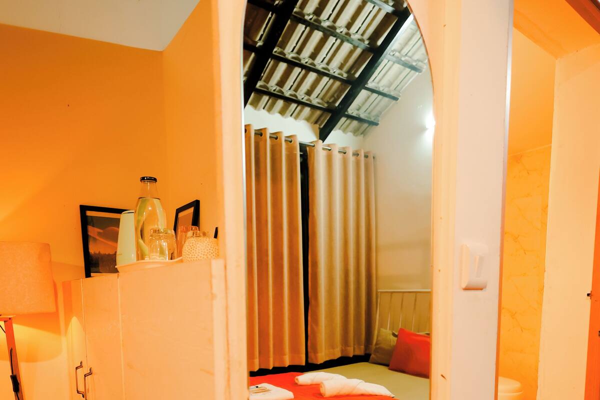 Une chambre à coucher avec un lit, une armoire et une salle de bain visible à travers une arche.