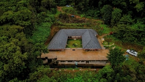 An aerial view of a traditional building with a central courtyard, surrounded by dense forest.