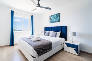 Ein modernes Schlafzimmer mit Bett, Deckenventilator, Nachttisch und einem Fenster mit Vorhängen.