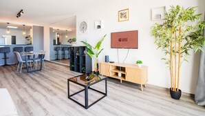 Ein modernes Wohnzimmer mit Essbereich, Fernseher und einer großen Pflanze.