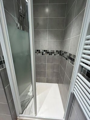 A shower with a glass door, tiled walls, and a white floor. - T3 air-conditioned with garden 900 m from the beach (Fréjus)