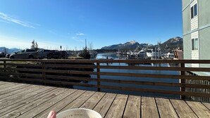 Eine Holzterrasse mit Blick auf einen Yachthafen und Berge im Hintergrund.