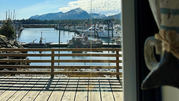 Eine Holzterrasse mit Blick auf eine Marina, Boote und Berge.