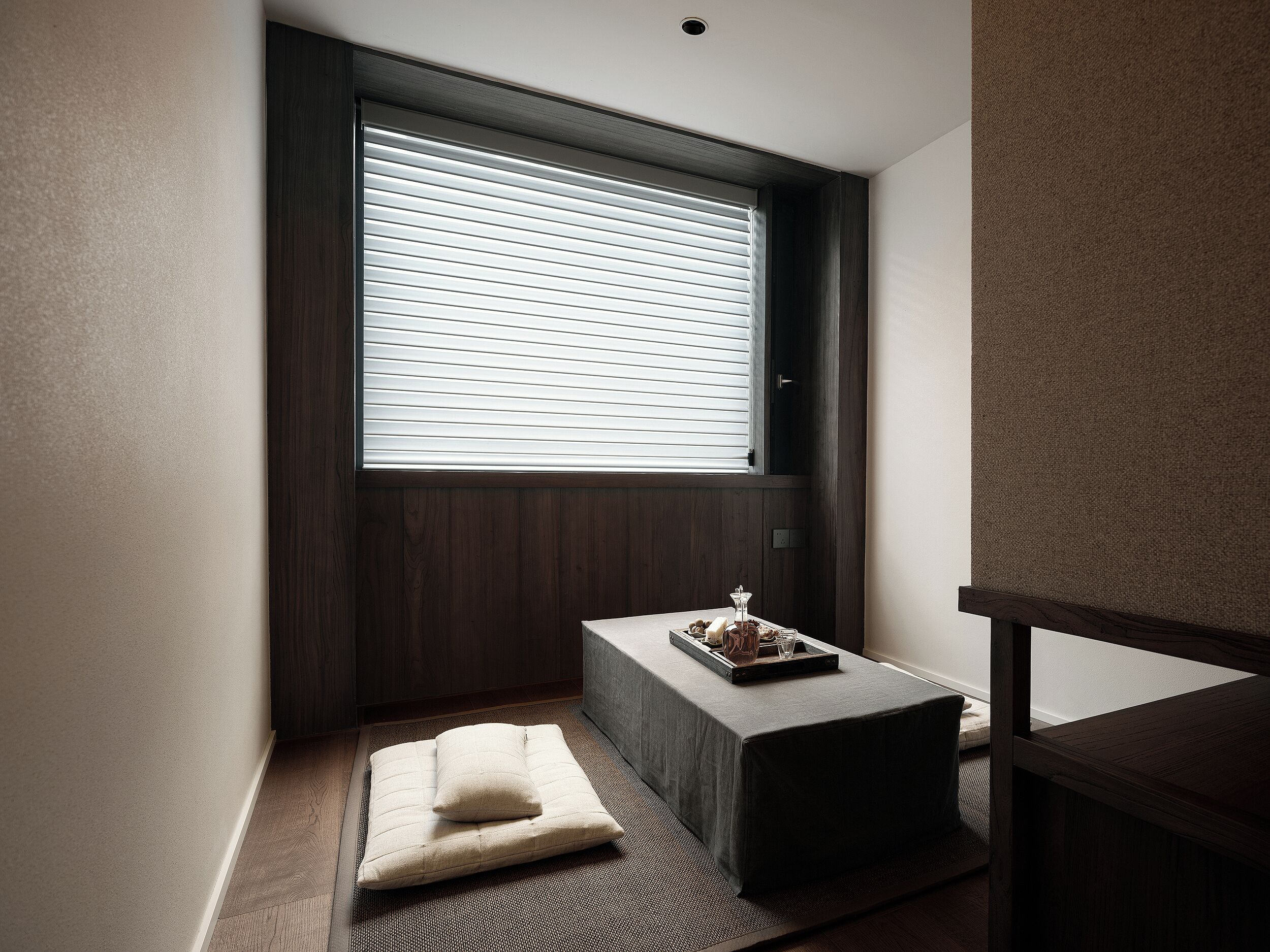 A minimalist room with a large window, a small bench, and a tray with items on it.