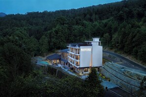 A modern hotel with multiple floors, surrounded by dense forest, and accessible by a winding road. - Zhangjiajie national park Oxgen Resort (Zhangjiajie)