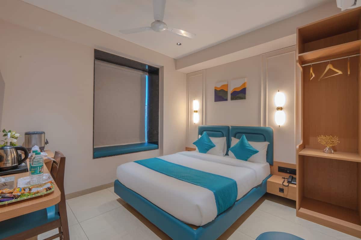 A hotel room with a bed, bedside table, desk, and a wardrobe.