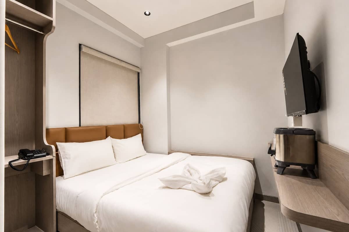 Una habitación de hotel con cama, teléfono, televisión y cafetera.