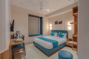 Ein Hotelzimmer mit Bett, Schreibtisch, Stuhl und Fenster.