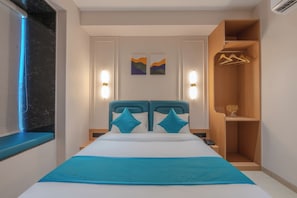 Ein modernes Hotelzimmer mit einem Bett, Nachttischen, einem Kleiderschrank und Kunstwerken an der Wand.