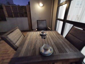 A wooden table with four chairs, a small table lamp, and a glass with a lid. - *Quiet, Cozy & Family-Friendly | Pool, Gym, Shops & Transport Nearby (Northshore)