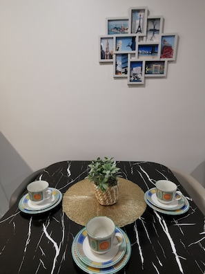 Ett matbord med en svart marmorskiva, omgivet av stolar, och en stor krukväxt i mitten.