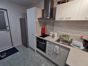 A compact kitchen with a refrigerator, oven, dishwasher, and a coffee maker.
