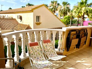 A balcony with a chair, a railing, and a building with a tiled roof in the background. - Apartment in Cabo Roig, 300 meters from the beach (VC)