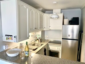 A kitchen with white cabinets, a stainless steel refrigerator, a built-in oven, a sink, and a wine bottle. - Apartment in Cabo Roig, 300 meters from the beach (VC)