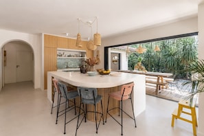 A modern kitchen with a central island, bar stools, and a view of the garden. - Beautiful villa ideally located with heated pool, 4*, 5 bed, Arcachon (Arcachon)