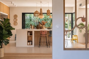 A modern kitchen with a central island, hanging wicker pendant lights, and a view of greenery outside. - Beautiful villa ideally located with heated pool, 4*, 5 bed, Arcachon (Arcachon)