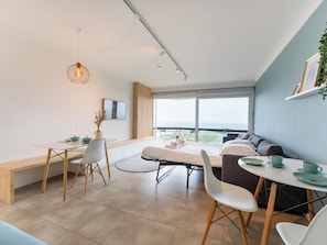Ein modernes Zimmer mit einem Bett, einem Esstisch und einer Couch.