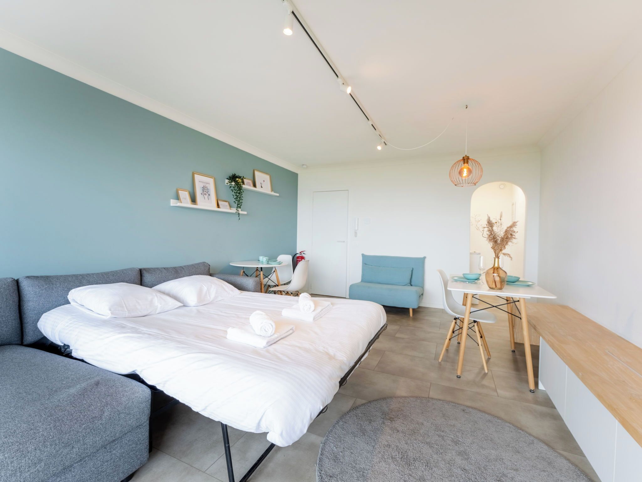 Een moderne hotelkamer met een bed, zithoek en een klein tafeltje met een vaas.