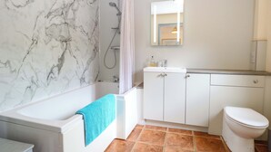 Ein Badezimmer mit einer Badewanne, einer Dusche, einer Toilette und einem Waschbecken mit Spiegel darüber.