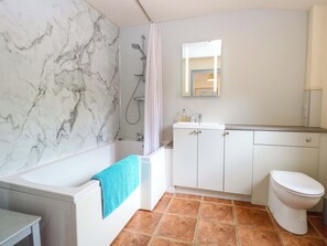Ein Badezimmer mit einer Badewanne, einer Dusche, einer Toilette und einem Waschbecken mit Spiegel darüber.
