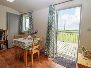 Ein Essbereich mit Tisch, Stühlen, einem Bücherregal und Blick auf einen Balkon.