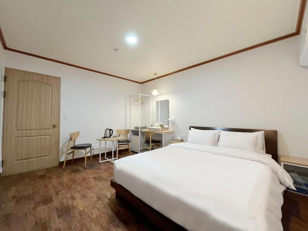 A hotel room with a bed, a desk, a chair, a wardrobe, and a mirror.