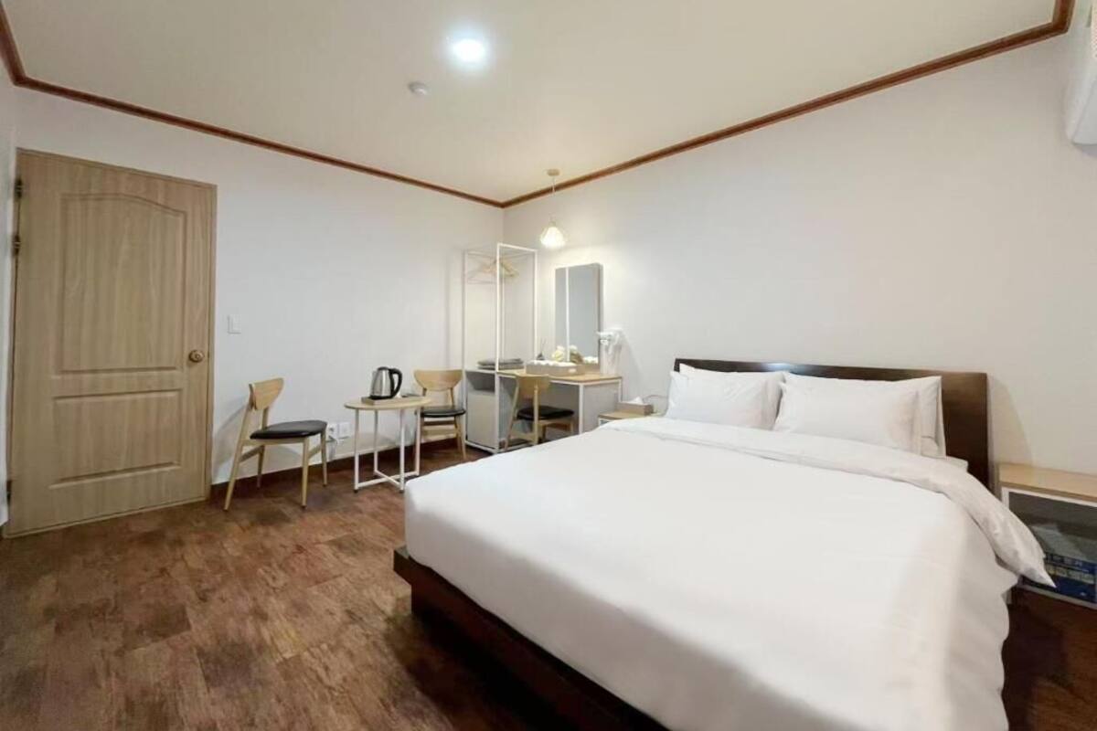A hotel room with a bed, a desk, a chair, a wardrobe, and a mirror.